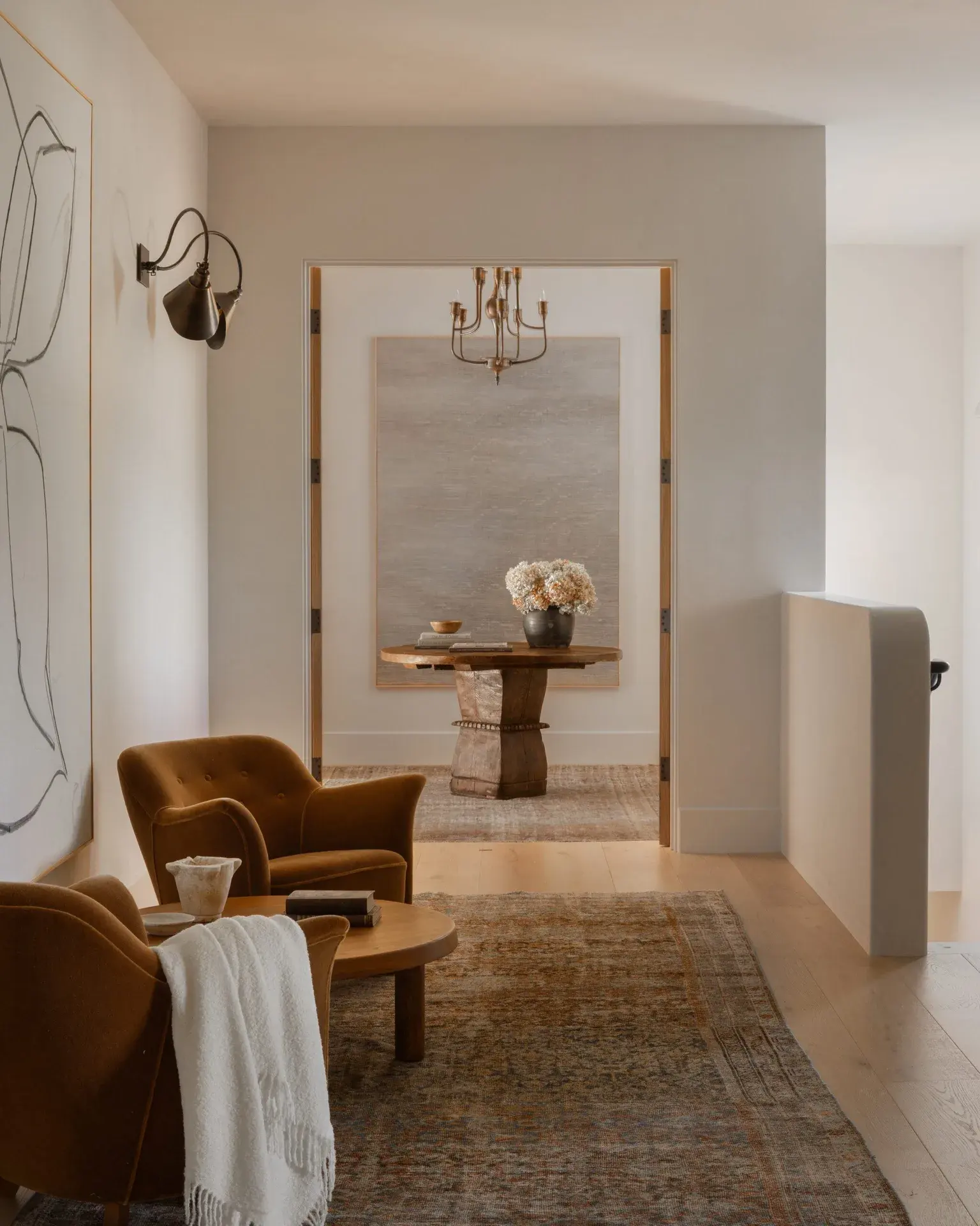 Sunlit sitting room with camel armchairs and a round oak table